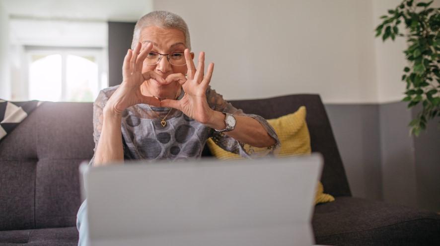 Senior woman giving the heart symbol to a friend over a video call.