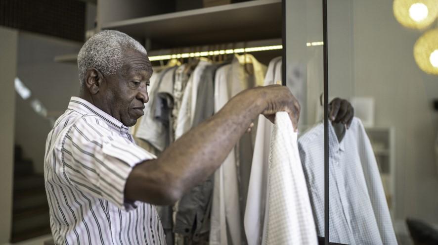 Senior man picking out a shirt to wear.