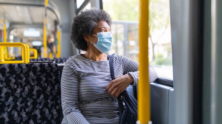 Senior woman on bus wearing mask.