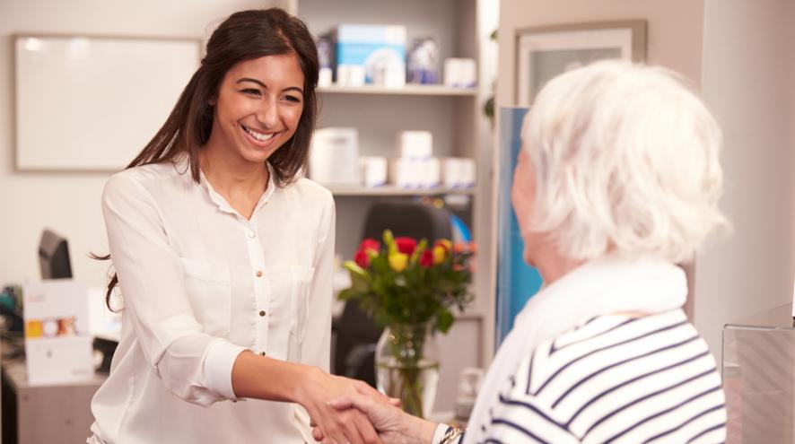 Friendly young physician greeting her senior client.