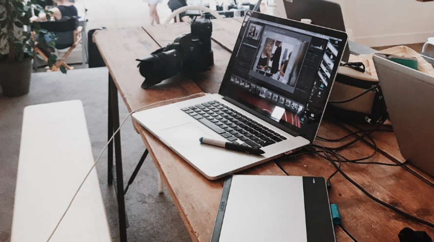 Picture of a desk with a camera, computer, photos and more.